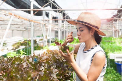 Young woman wearing hat standing by flowering plants