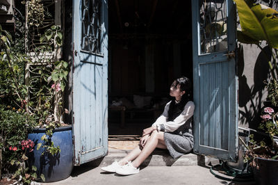Full length of woman sitting outside house
