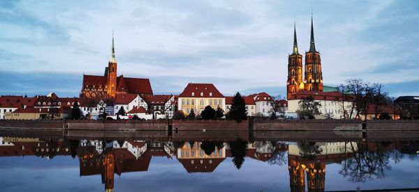 Reflection of buildings in lake against sky in city