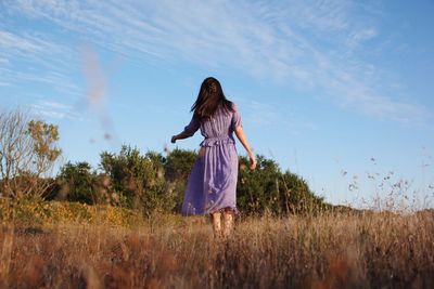 Woman standing on field against sky