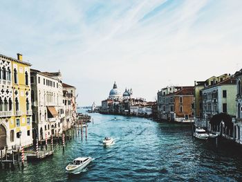 Boats sailing on canal amidst buildings