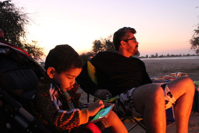 Friends sitting on car against sky