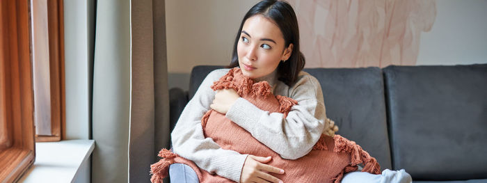 Portrait of young woman sitting on sofa at home