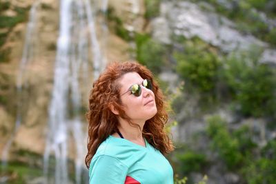 Portrait of woman standing against waterfall