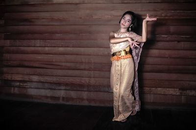 Full length of girl in traditional clothing dancing against wall