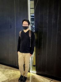 Portrait of young man standing against wall