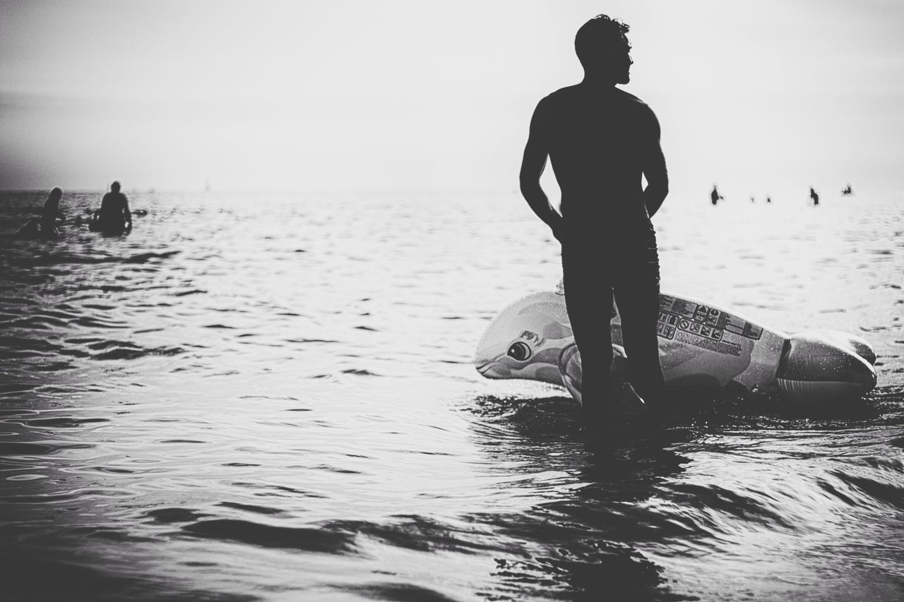 water, silhouette, sea, lifestyles, leisure activity, men, horizon over water, clear sky, full length, reflection, standing, waterfront, sky, person, tranquility, nature, tranquil scene, beach