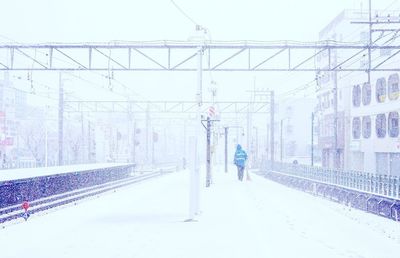 Rear view of people walking on snow covered bridge