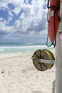 A lifebuoy and lifeline at a wild tropical beach in mexico, ocean and partly cloudy sky 