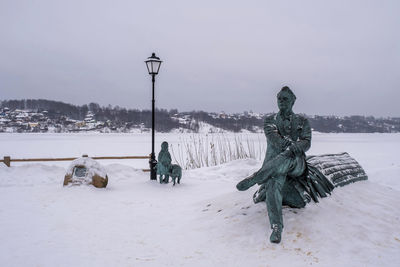 Statue on snow covered field against sky