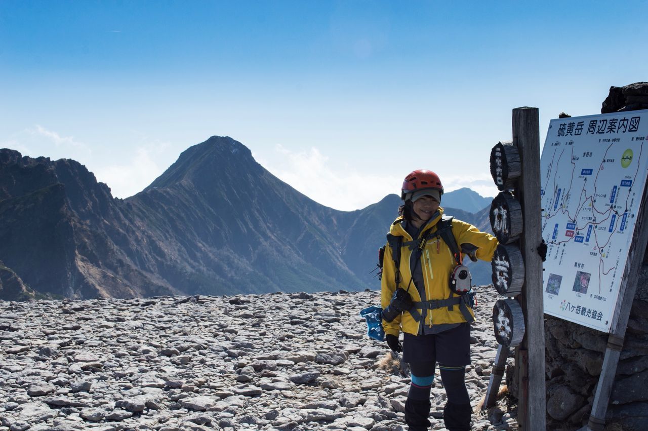 MAN STANDING ON SNOW COVERED MOUNTAINS