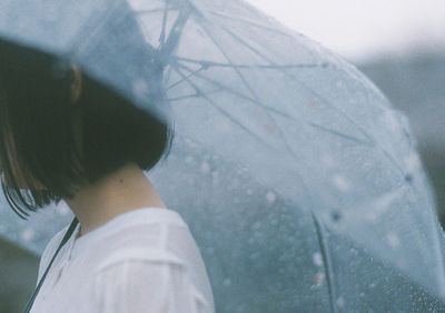 Rear view of woman on wet window during rainy season