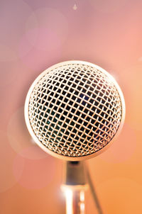 Extreme close-up of microphone against colored background