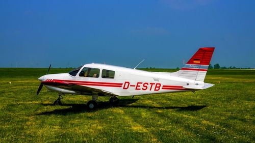 Side view of airplane on field against sky