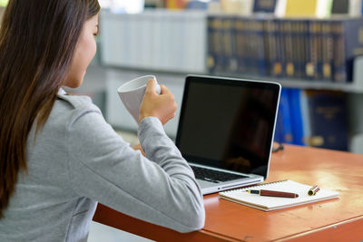 Midsection of woman using laptop on table