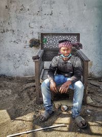 Portrait of young man sitting on wall