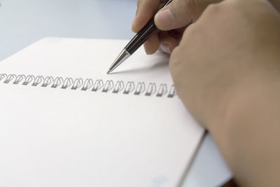 Cropped image of person writing in book