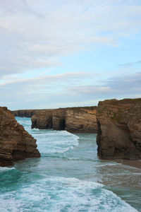 Rock formations by sea against sky