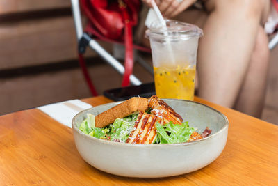 Woman eats healthy food caesar salad and fruit juice in restaurant.