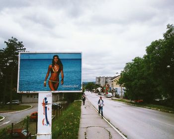 People on road against cloudy sky