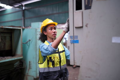 Portrait of young woman standing against building