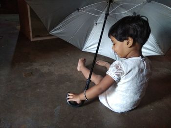 Cute girl with umbrella sitting at home