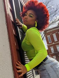 Low angle portrait of woman standing against wall