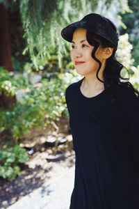 Middle-aged japanese woman in black straw sun brim hat, summer park