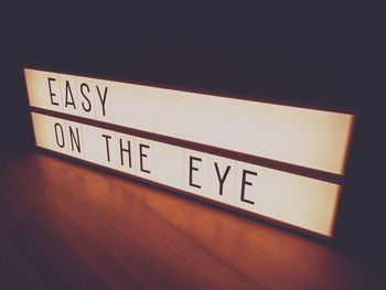 High angle view of illuminated text on wooden table in darkroom