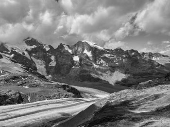 Scenic view of glacier by snowcapped mountains against sky