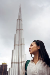 Low angle view of woman looking away against sky