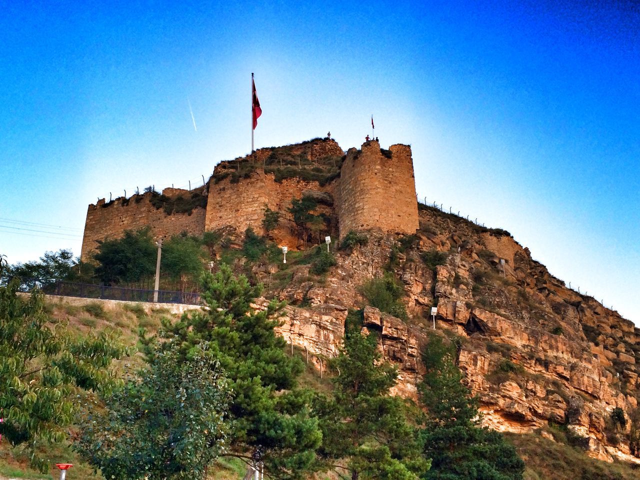 clear sky, blue, low angle view, built structure, architecture, building exterior, rock formation, history, copy space, sky, rock - object, sunlight, famous place, ancient, landscape, travel destinations, day, mountain, travel, hill