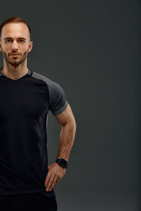 Portrait of young man standing against black background