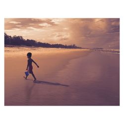 Full length of man on sea against sky during sunset