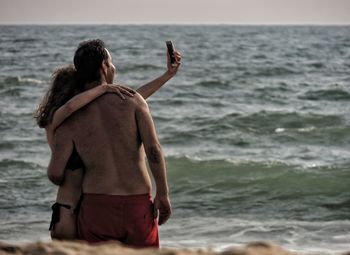 Couple taking selfie with smart phone at beach