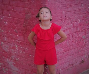 Full length of a girl standing against red brick wall