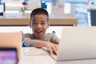 Boy using mobile phone at table