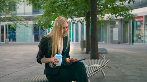 Rear view of woman using mobile phone in city