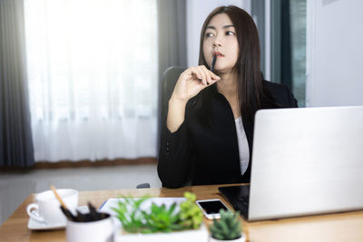 Young woman using phone while sitting on table