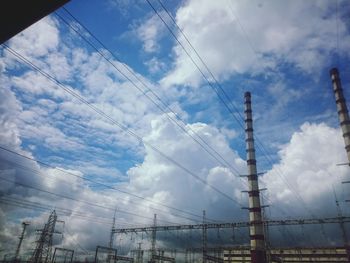 Low angle view of electricity pylon against cloudy sky