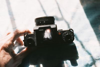 Cropped hand holding camera on sunny day