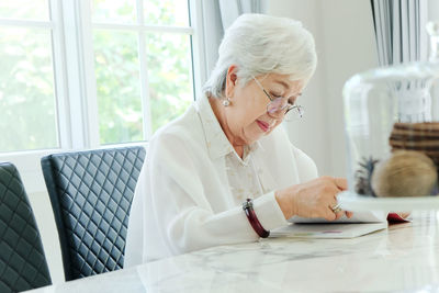 Senior woman reading book while sitting at home