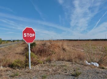 Road sign on field against sky