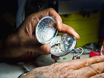 Cropped hands of man repairing pocket watch on table