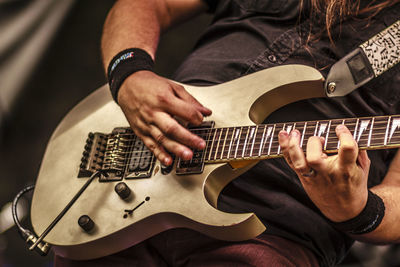 Midsection of man playing guitar during concert