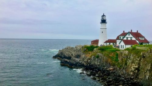 Lighthouse by sea against sky