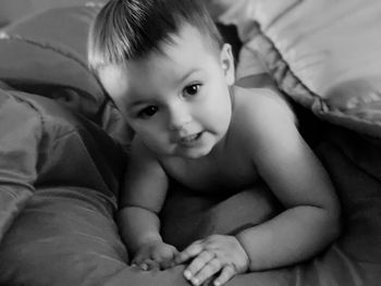 Portrait of cute boy lying on bed at home