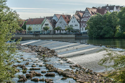 Buildings by river against sky