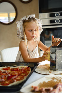 Little girl cooking pizza in the kitchen