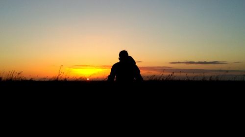 Silhouette man on field against clear sky during sunset